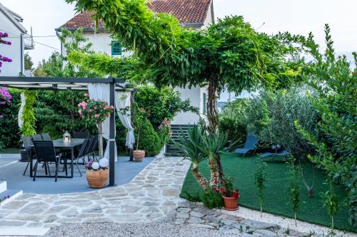 einen Garten mit einer Terrasse, einem Tisch und Stühlen in der Unterkunft Modern apartment with an outdoor jacuzzi in Brodarica
