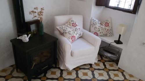 een woonkamer met een witte stoel en een open haard bij Wunderschönes Ferienhaus in Andalusien in Montejaque