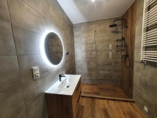 a bathroom with a sink and a shower with a mirror at Słoneczny Zakątek in Pogorzelica