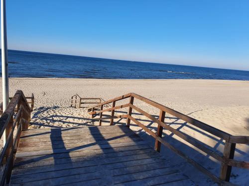 a wooden boardwalk leading to the beach with the ocean at Słoneczny Zakątek in Pogorzelica