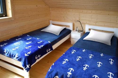 two beds in a room with blue sheets and white pillows at Nadmorskie Klimaty - Domki Całoroczne in Stegna