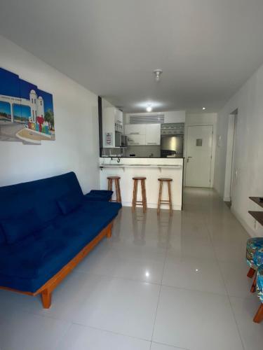 a living room with a blue couch and a kitchen at APARTAMENTO EM ARRAIAL DO CABO - RJ in Arraial do Cabo