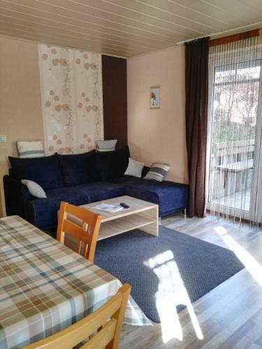 a living room with a blue couch and a table at Ferienwohnungen Hochgrebe in Kleinern