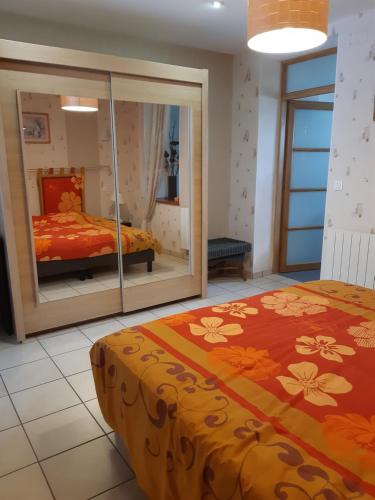 a bedroom with a bed and a mirror at Gîte AUX 3 PTITS COCHONS in Cuisiat