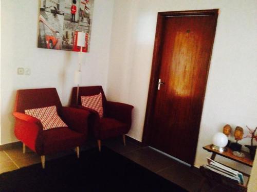 a living room with two chairs and a wooden door at Residencial Ponto Certo in Vilar Torpim