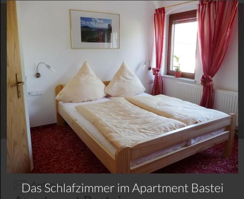 a bedroom with a bed with red curtains and a window at Guesthouse Elbsandstein App. Bastei in Rathmannsdorf