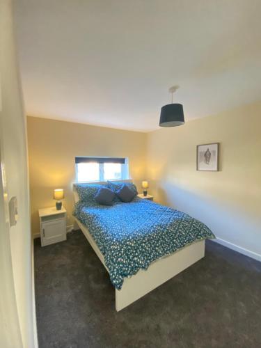 a bedroom with a bed with blue sheets and a window at Hodge Bower Holidays, Ironbridge - Sedgwick in Ironbridge