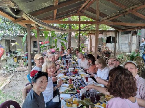 un grupo de personas sentadas en una mesa larga con comida en Posada Maná, en San Juan La Laguna