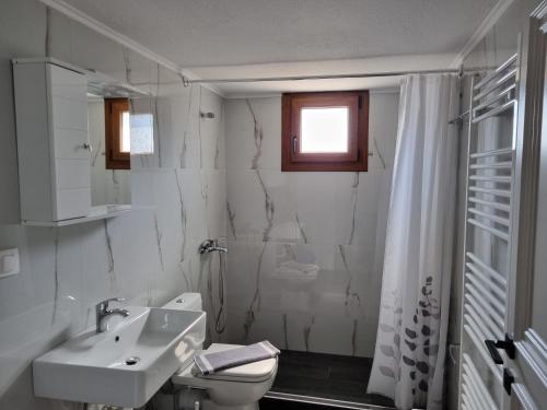 a white bathroom with a sink and a toilet at Chriselia House in Nea Roda