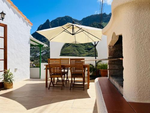 a table and chairs with an umbrella on a patio at Jardín de La Suerte in Agaete