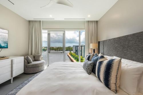 a bedroom with a large white bed with a large window at Cayman Luxury Rentals at One Canal Point in Upper Land