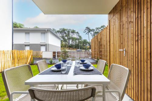 une table blanche et des chaises sur une terrasse dans l'établissement Magnifique villa 4 pers à 10 min de la plage à pied, à Seignosse