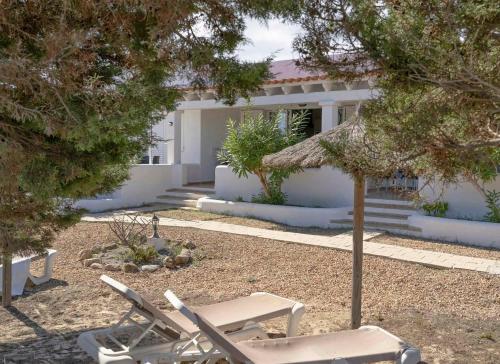 a house with two lawn chairs in front of it at Roquetes Bungalows Premium - Formentera Break in Es Pujols