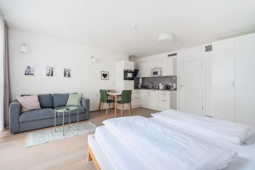 a white bedroom with two beds and a couch at Quiet and cozy apartment next to Mariahilfer Strasse and Naschmarkt with AC in Vienna