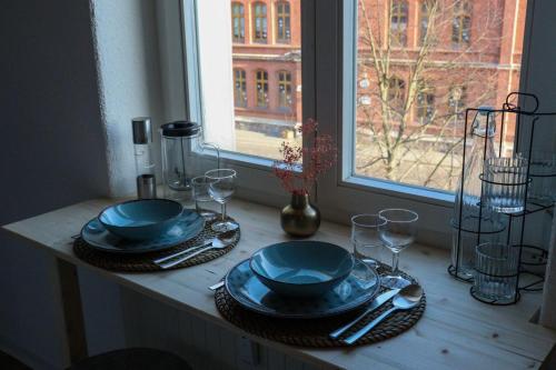 a table with blue plates and glasses and a window at Studio 11 in Torgau
