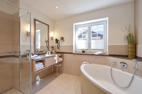 a bathroom with a tub and a sink at Villa Ludwig Suite Hotel in Hohenschwangau