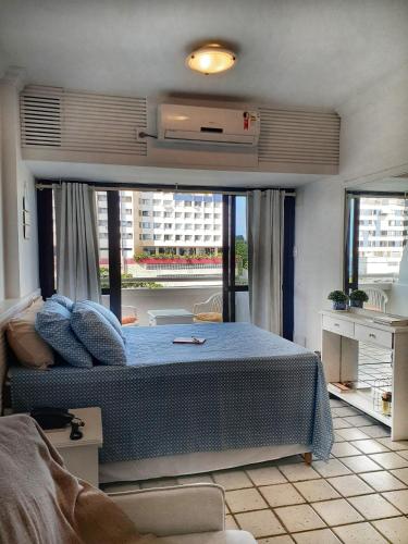 a bedroom with a bed and a large window at Studio encantador em Ondina in Salvador