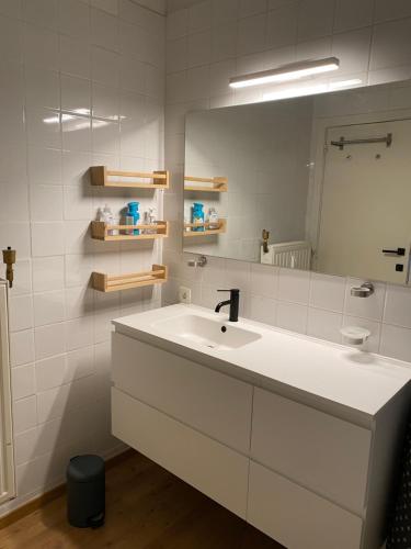 bagno bianco con lavandino e specchio di Appartement Fr Gilkens Ostende a Ostenda