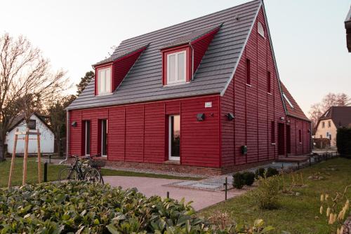een rode schuur met een gambrel dak bij Ferienwohnung Rote Kate in Born