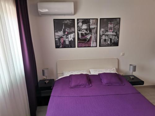 a bedroom with a purple bed with pictures on the wall at Sea Gate Studio in Zadar