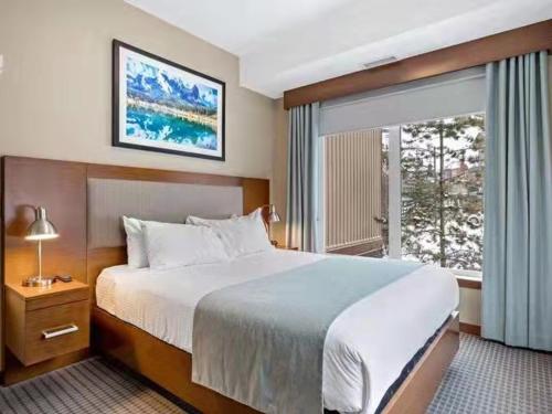 a hotel room with a large bed and a window at Sunny Tranquil Woods Turret in Falcon Crest Lodge in Canmore