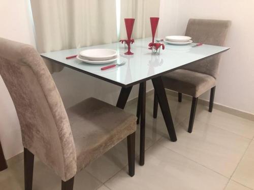 a dining room table with two chairs and a table with plates at Loft Casa Feliz in Rio das Ostras
