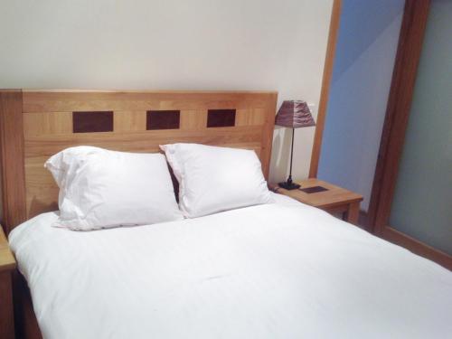 a bed with white sheets and pillows and a lamp at Little Glebe Cottage in Durrus