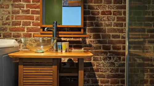 La salle de bains est pourvue d'un lavabo et d'un mur en briques. dans l'établissement Little Suite - Coline, à Lille