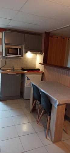 a small kitchen with a table and a microwave at Les Caraïbes in Peyrehorade