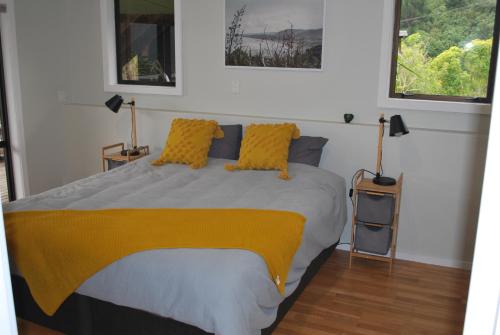 1 Schlafzimmer mit einem Bett mit gelber Bettwäsche und 2 Fenstern in der Unterkunft Kea Ridge King Ensuite Room in Riwaka