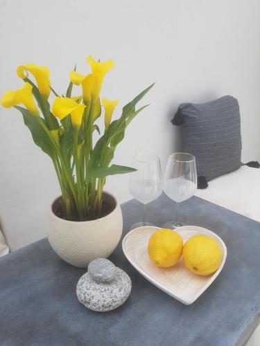 a table with two glasses and a vase with yellow flowers at Cassaris Mykonos in Drafaki
