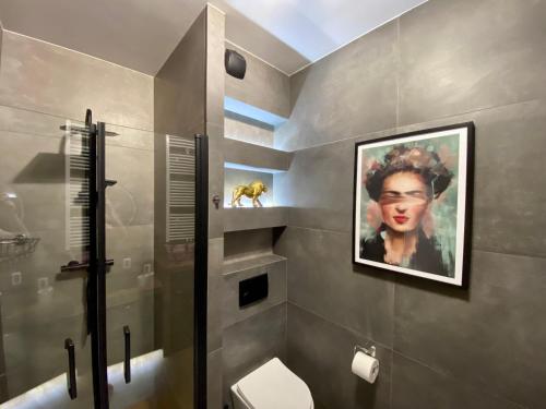 a bathroom with a painting of a woman on the wall at Chlebova Apartments in Gdańsk