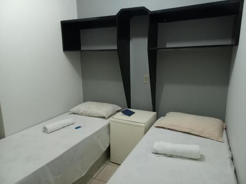 a small room with two beds and a refrigerator at Noite hotel in Palmas