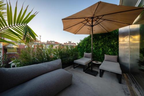 eine Terrasse mit einem Sofa, einem Sonnenschirm und Stühlen in der Unterkunft We Hate F Tourists in Lissabon