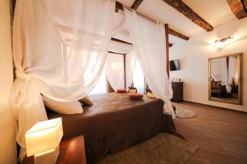 1 dormitorio con cama con dosel y cortinas blancas en Luxury Rooms Contessa Vitali, en Zadar