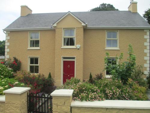 a brown brick house with a red door at Tralia Farmhouse Self Catering in Farranfore