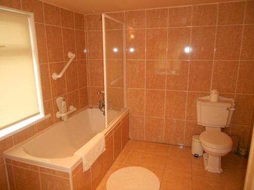 La salle de bains est pourvue d'une baignoire, de toilettes et d'une douche. dans l'établissement Tralia Farmhouse Self Catering, à Farranfore