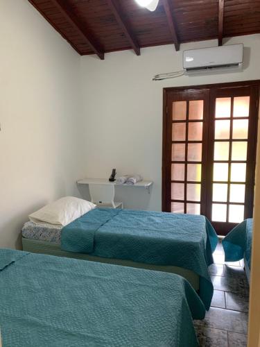 1 Schlafzimmer mit 2 Betten mit blauer Bettwäsche und einem Fenster in der Unterkunft Hotel Colonial Suites ,Bracel, Lwart, Zilor in Lençóis Paulista