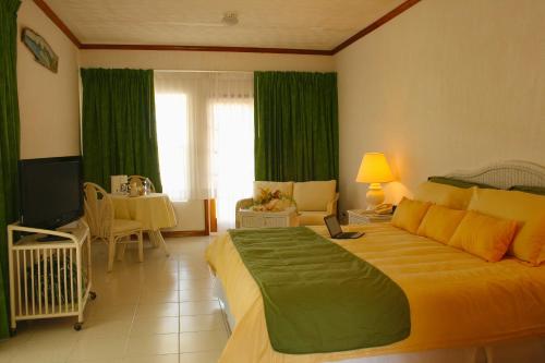- une chambre avec un grand lit et des rideaux verts dans l'établissement Unique Village, à Governorʼs Harbour