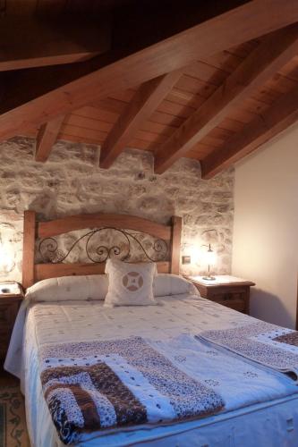 a bedroom with a bed in a stone wall at Hotel Rural Villa de Silos in Santo Domingo de Silos