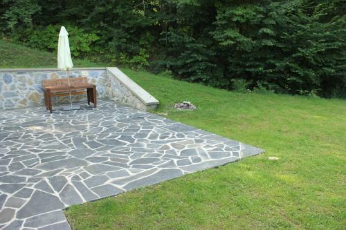 a bench sitting on a stone patio with an umbrella at Apartmány Maršíkov in Velké Losiny