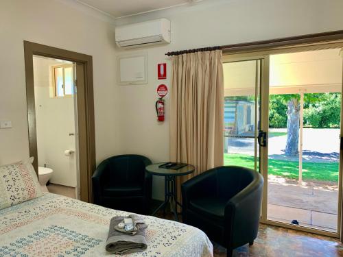 a bedroom with a bed and two chairs and a table at Cootamundra Caravan Park in Cootamundra