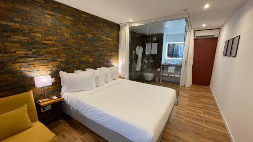 - une chambre avec un grand lit et un mur en briques dans l'établissement Vue Mer & Rocher - Okavango Blue Studio, au Diamant