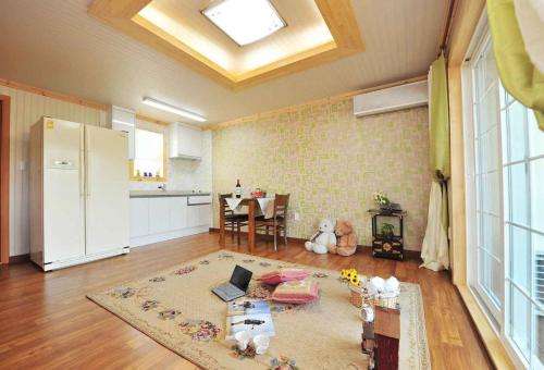 a living room with a kitchen and a table with a laptop at Prime Pension in Yangyang