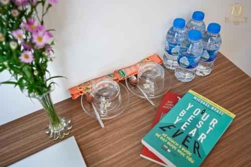 einen Tisch mit Brille, ein Buch und eine Vase mit Wasser in der Unterkunft Napoly Hotel in Vũng Tàu