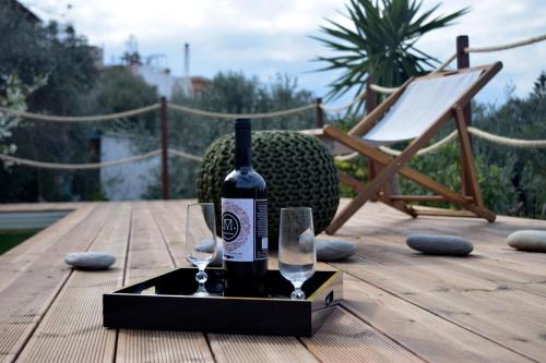a bottle of wine and two glasses on a wooden deck at Momentum Θ in Maleme