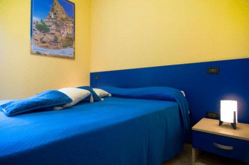 een slaapkamer met een blauw bed en een lamp op een tafel bij B&B Mare Nostrum in Catona