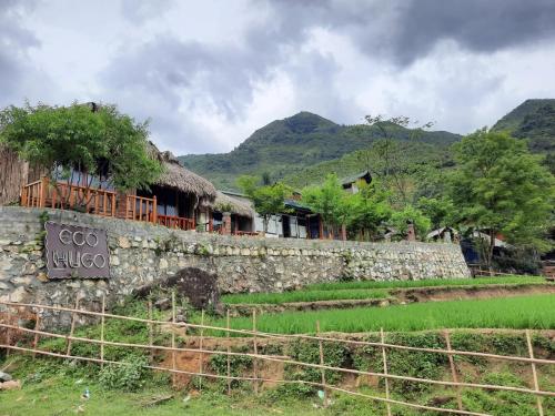 a stone wall in front of a village with mountains at Sapa Eco Hugo in Sa Pa