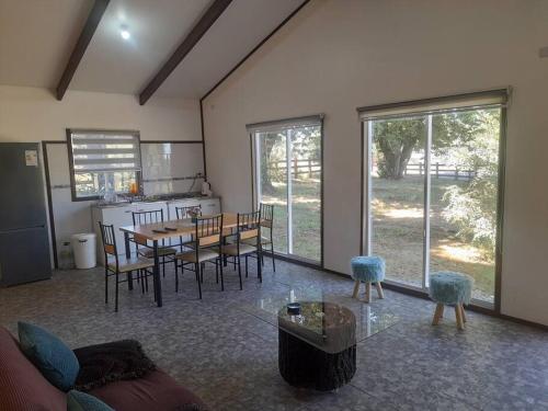 a living room with a table and chairs and a kitchen at Hermosa cabaña en parcela a 500 metros del centro. in Cunco