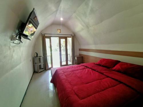 a bedroom with a red bed and a window at Pagupon Camp Syariah in Batu